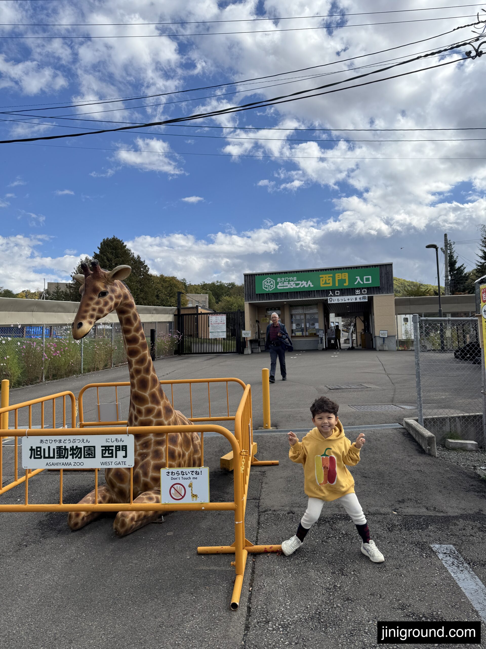 Child in yellow jacket feeding giraffe at Asahiyama Zoo animal encounter