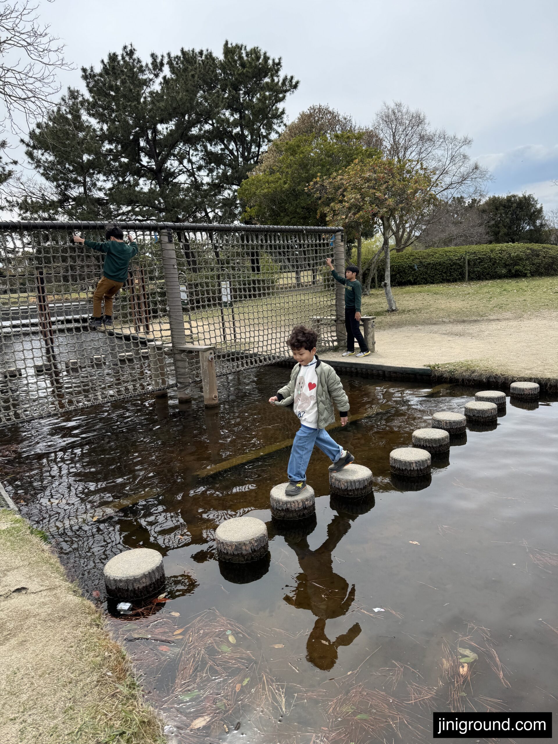 Young boy balancing on round stepping stones over water at Uminonakamichi Park playground Fukuoka