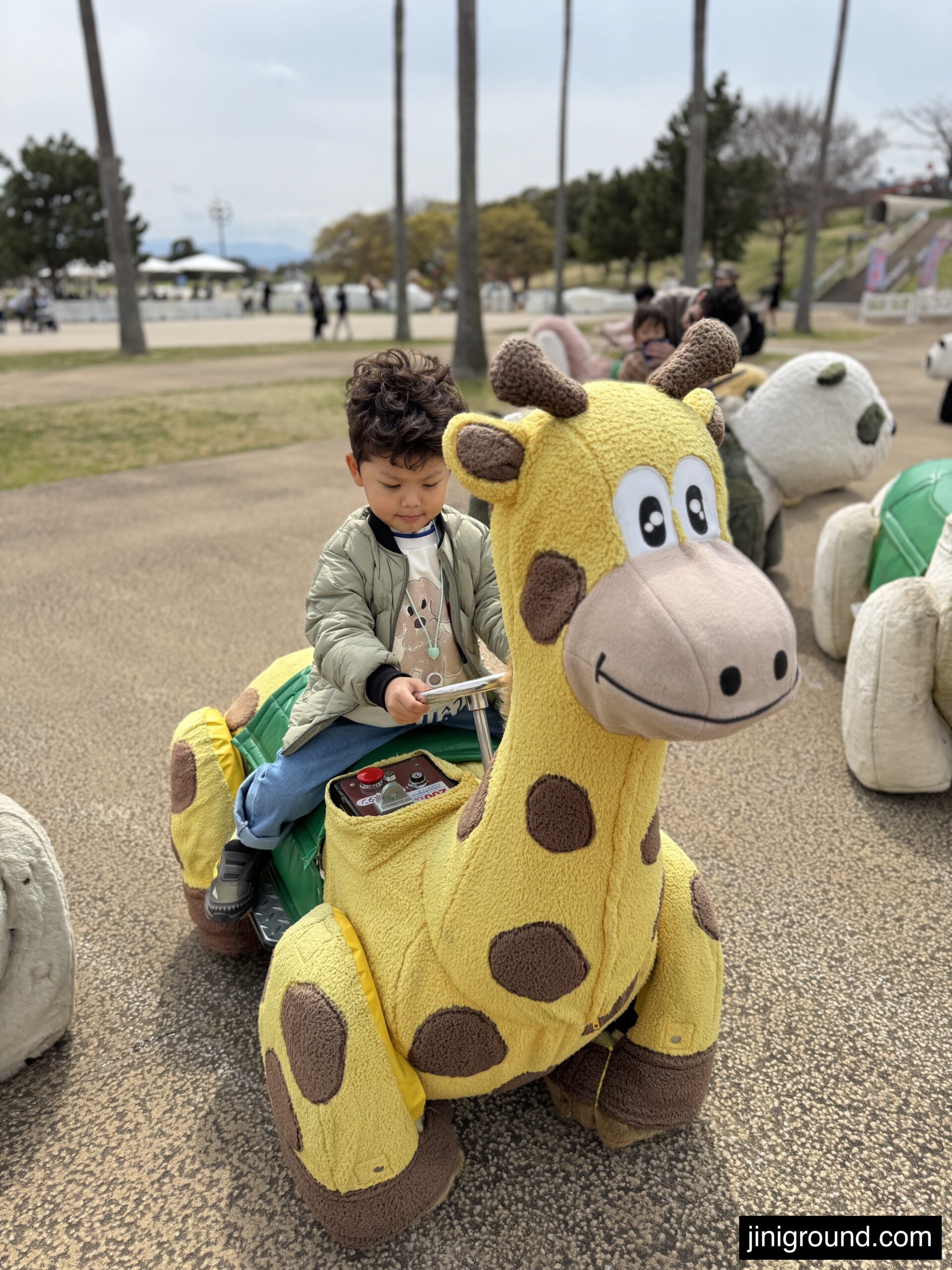 60 month old boy riding giraffe shaped toy ride at Uminonakamichi Seaside Park Fukuoka