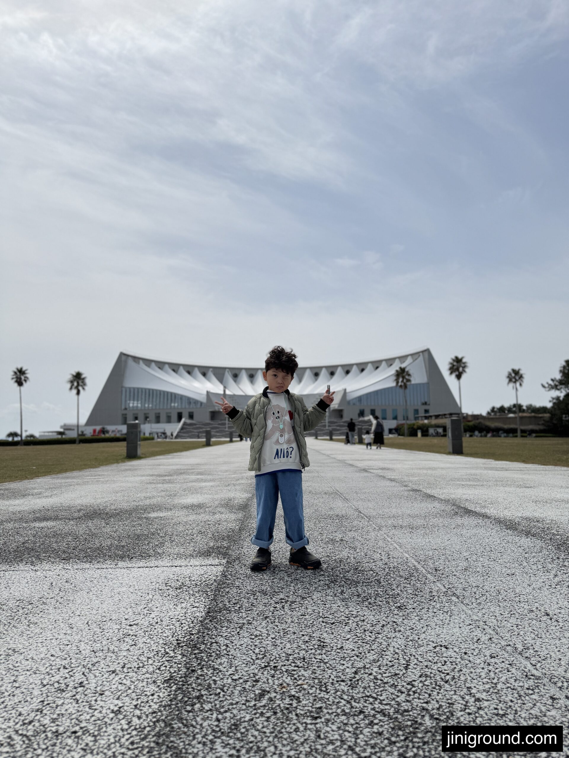 Boy standing on pathway with Marine World Uminonakamichi building in background Fukuoka Japan