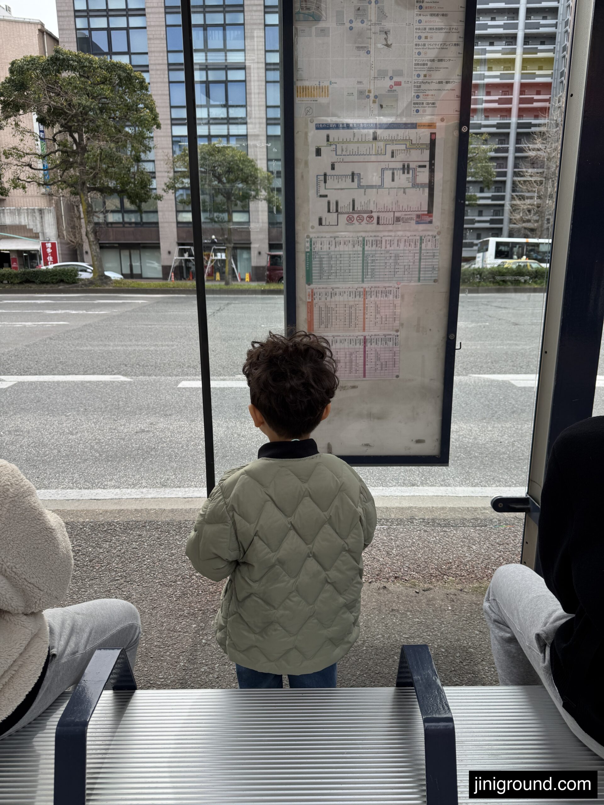 60 month old boy waiting at Nishitetsu bus stop in Fukuoka heading to Marine World aquarium