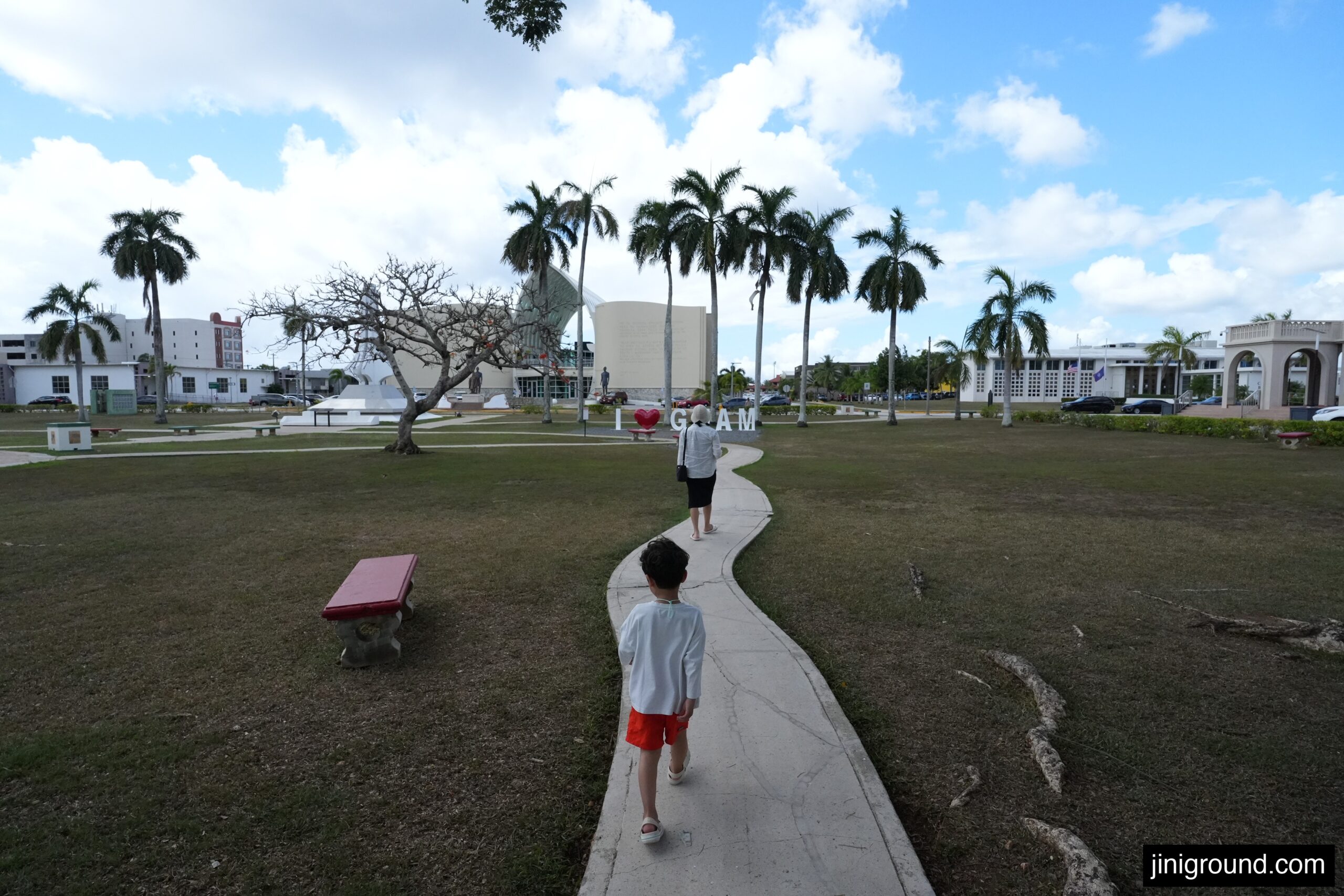 6 year old boy walking through Guam plaza with palm trees and I love Guam sign