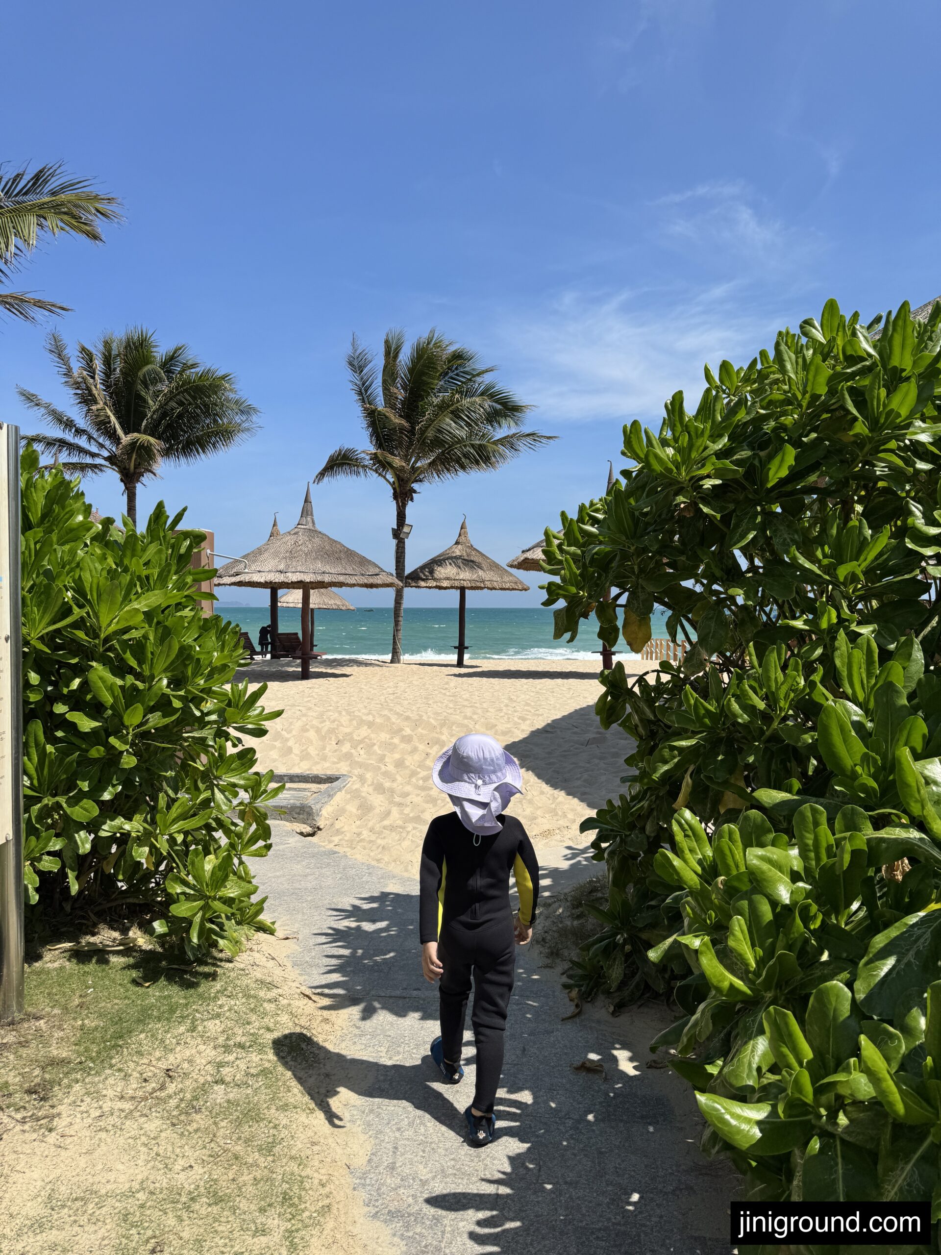 Boy walking through tropical garden path to private beach at Vinpearl Cam Ranh Resort