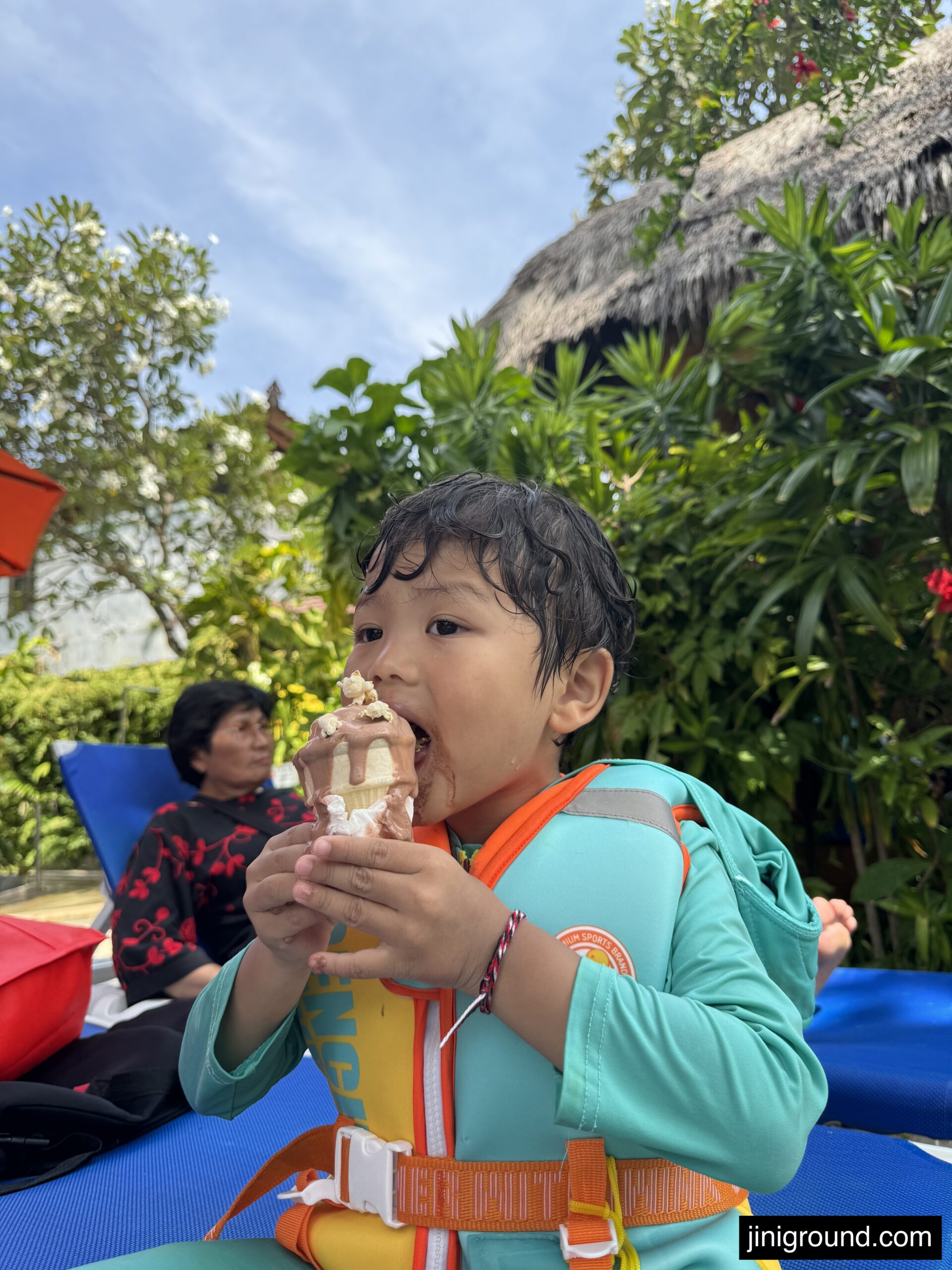 Child in yellow safety vest and life jacket at Waterbom Bali swimming area