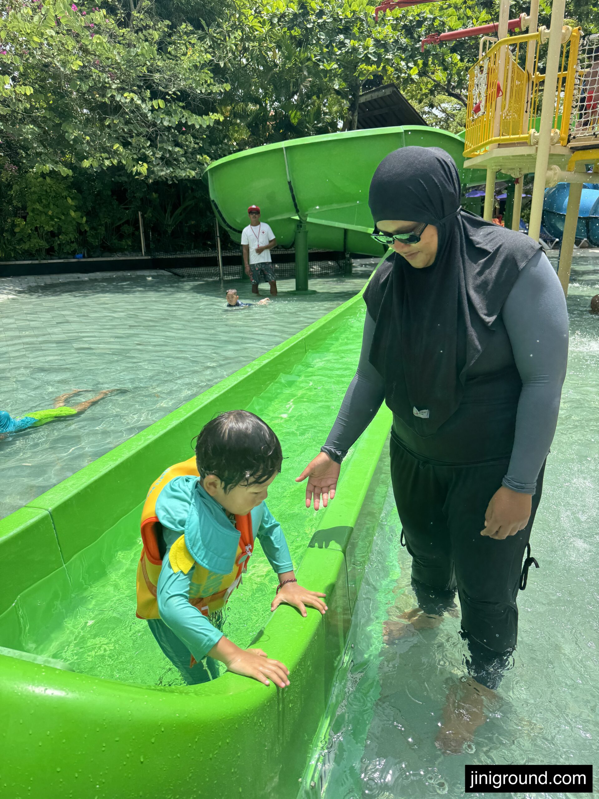 Young child in bright neon green swimming pool at Waterbom Bali park
