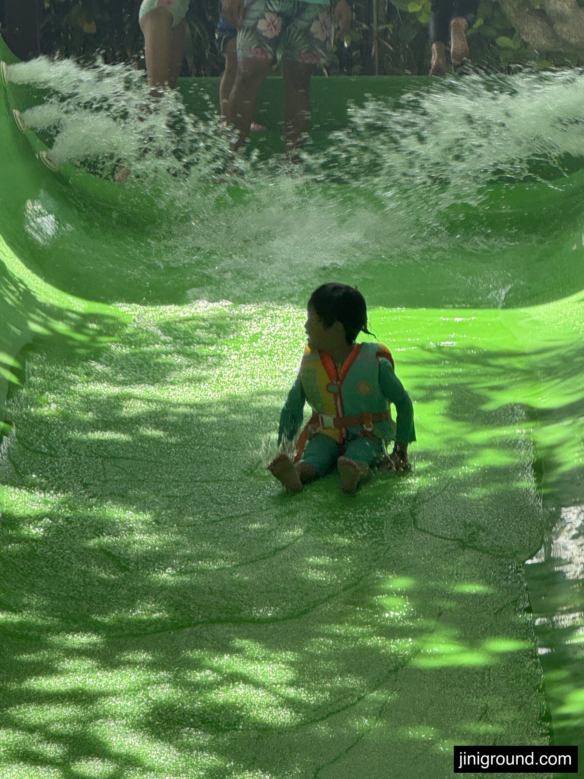 Child sliding down bright green water slide at Waterbom Bali water park