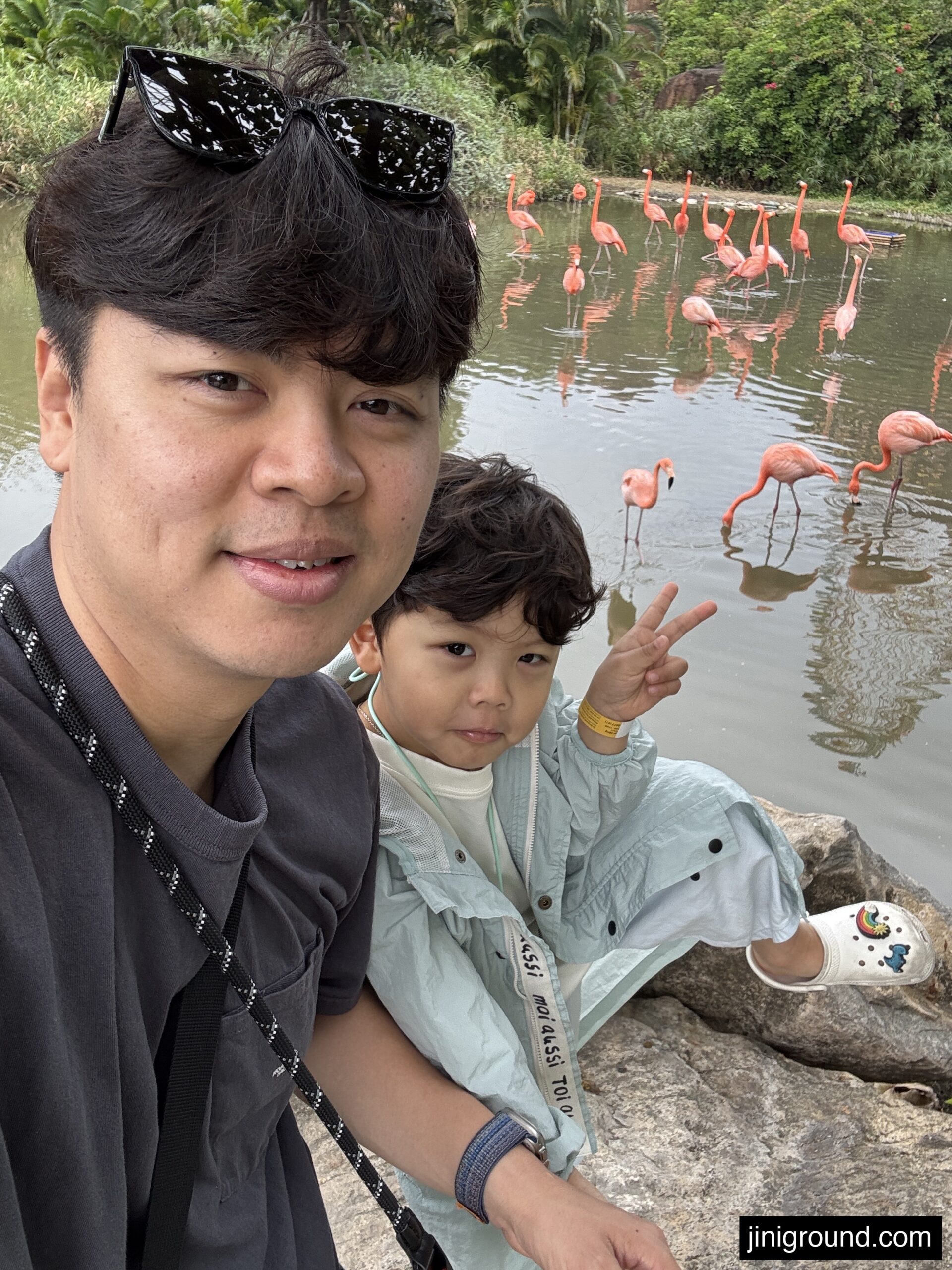 Father and son taking selfie with pink flamingos at VinWonders Nha Trang Vietnam