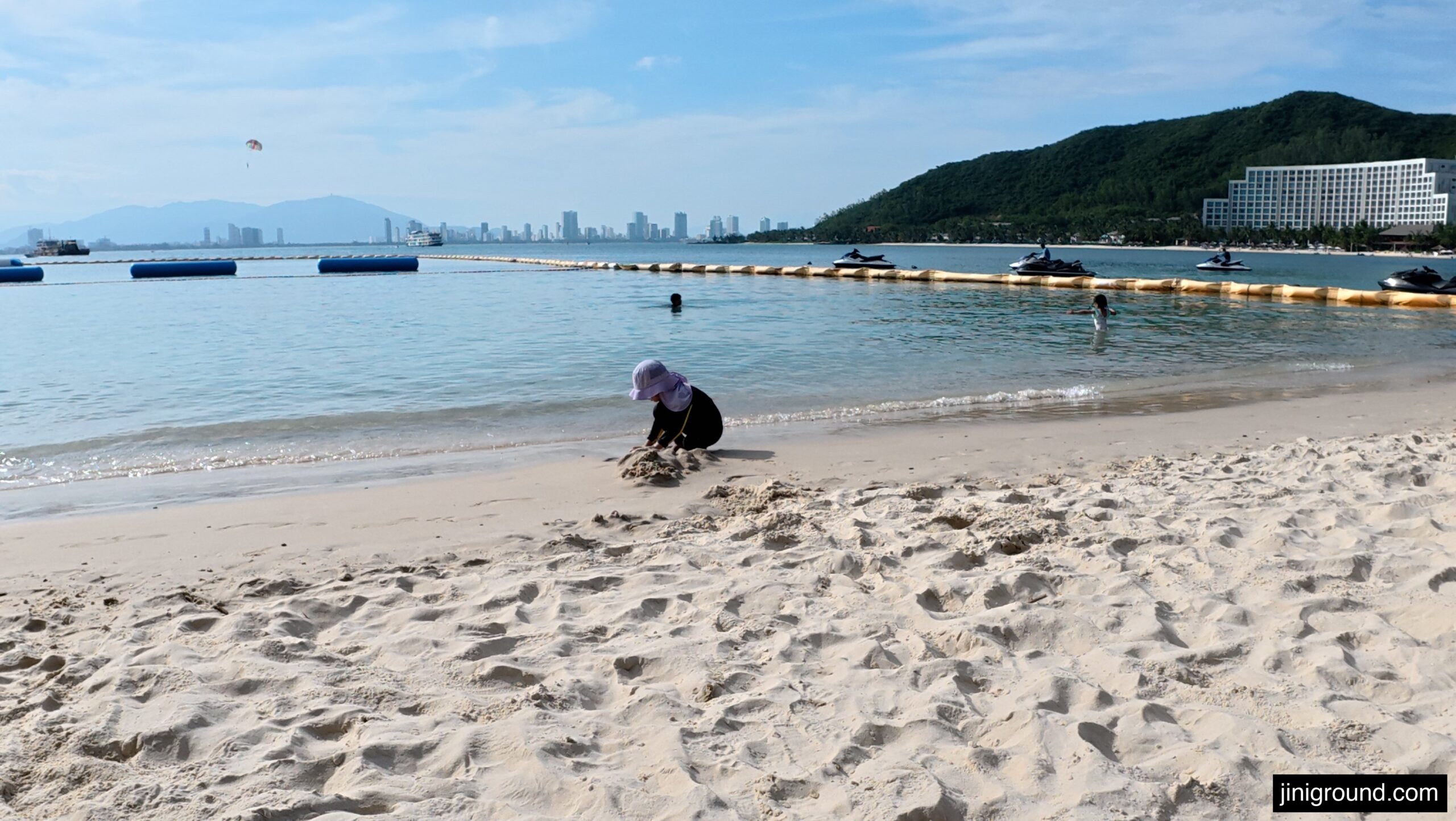 Aerial view of child playing in sand on VinWonders beach Nha Trang with city skyline
