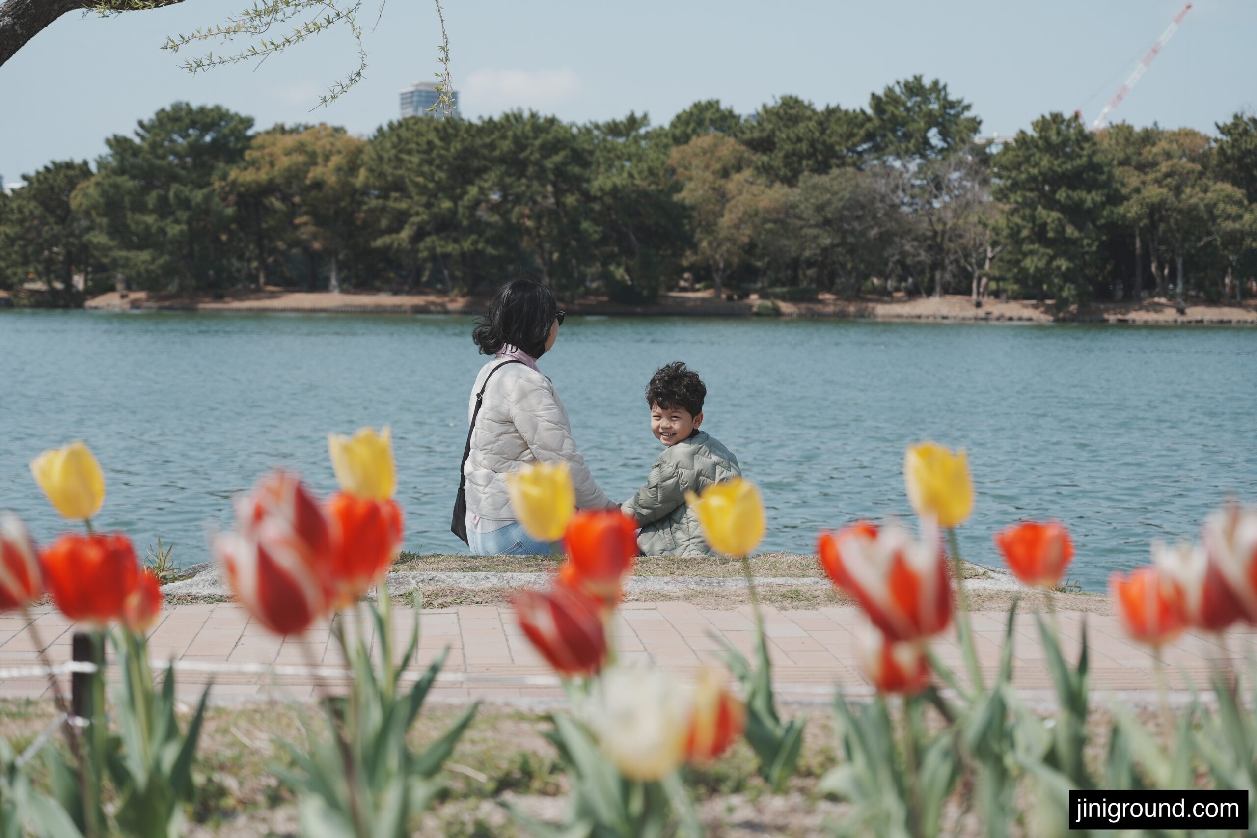 Mom and 60 month old son sitting by lake with colorful tulips at Ohori Park Fukuoka Japan