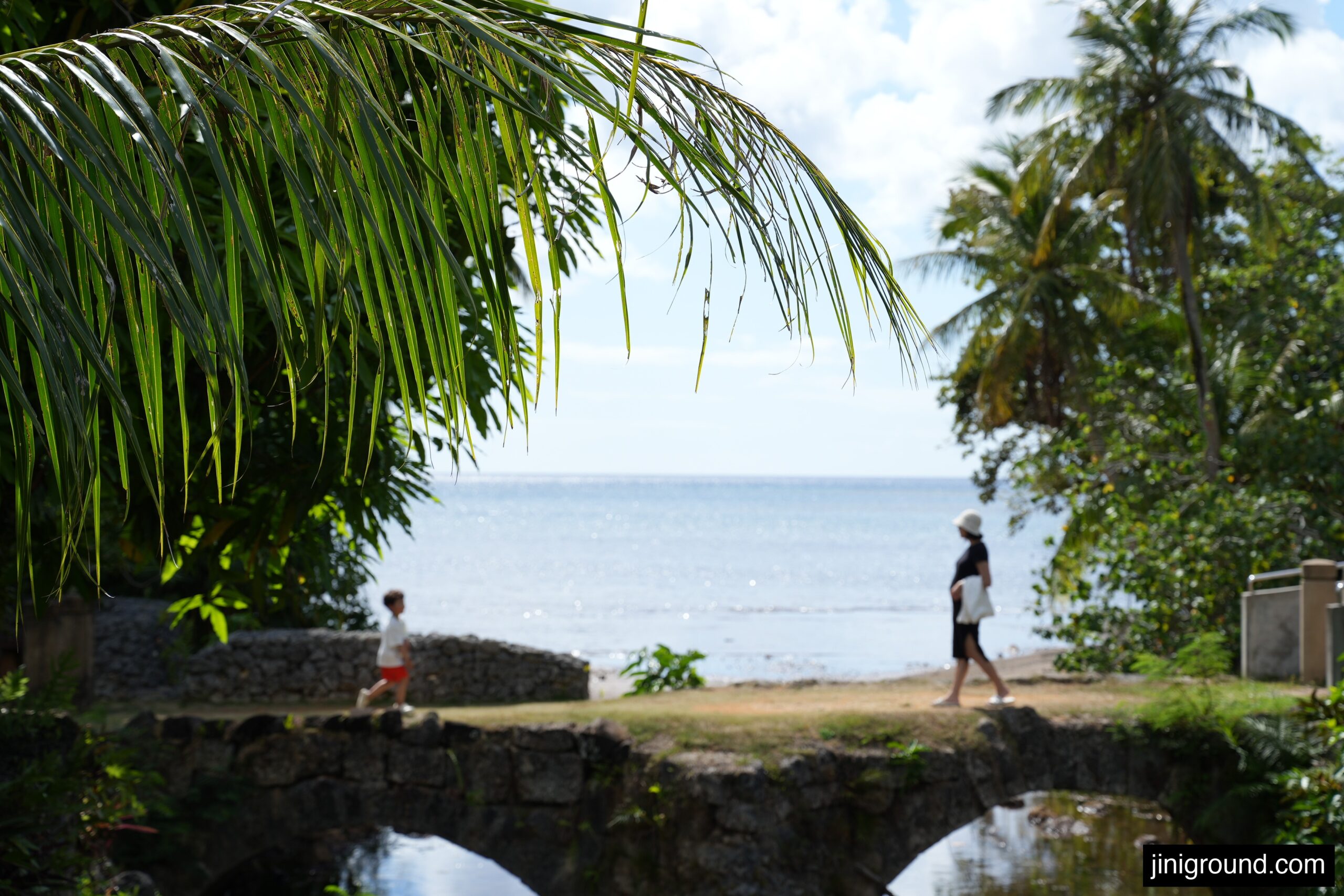 mom and son crossing stone bridge with ocean view during south Guam tour