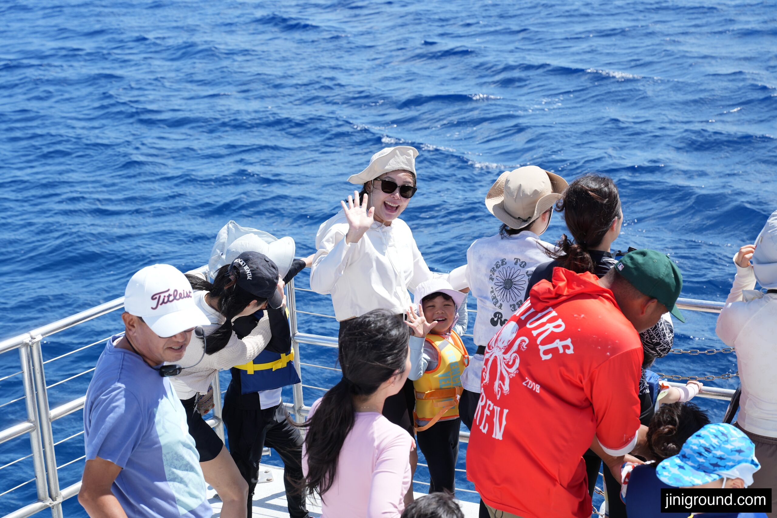 passengers watching dolphins from cruise boat railing in Guam ocean