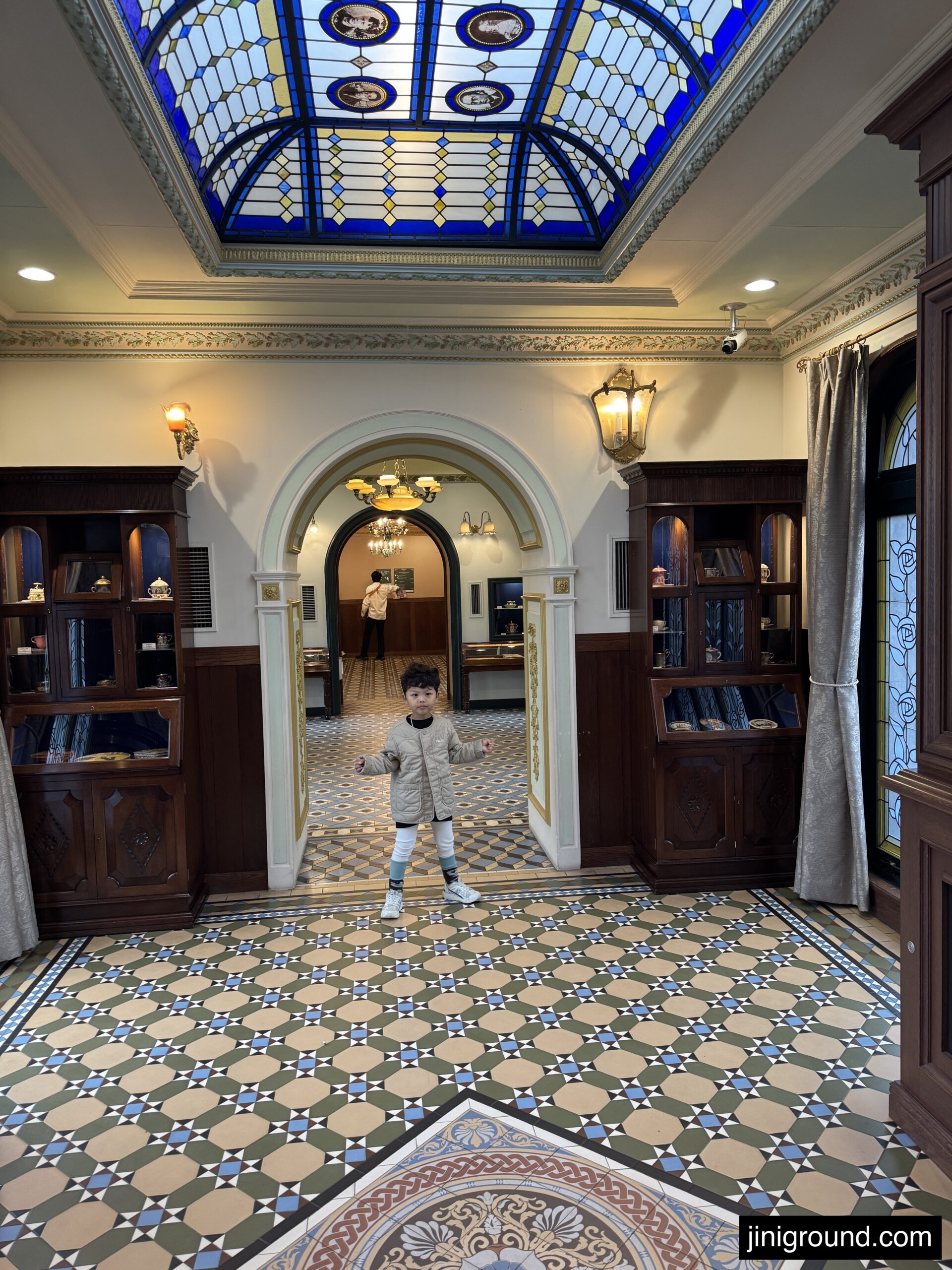 Child sitting with oversized colorful park mascot character statue Sapporo