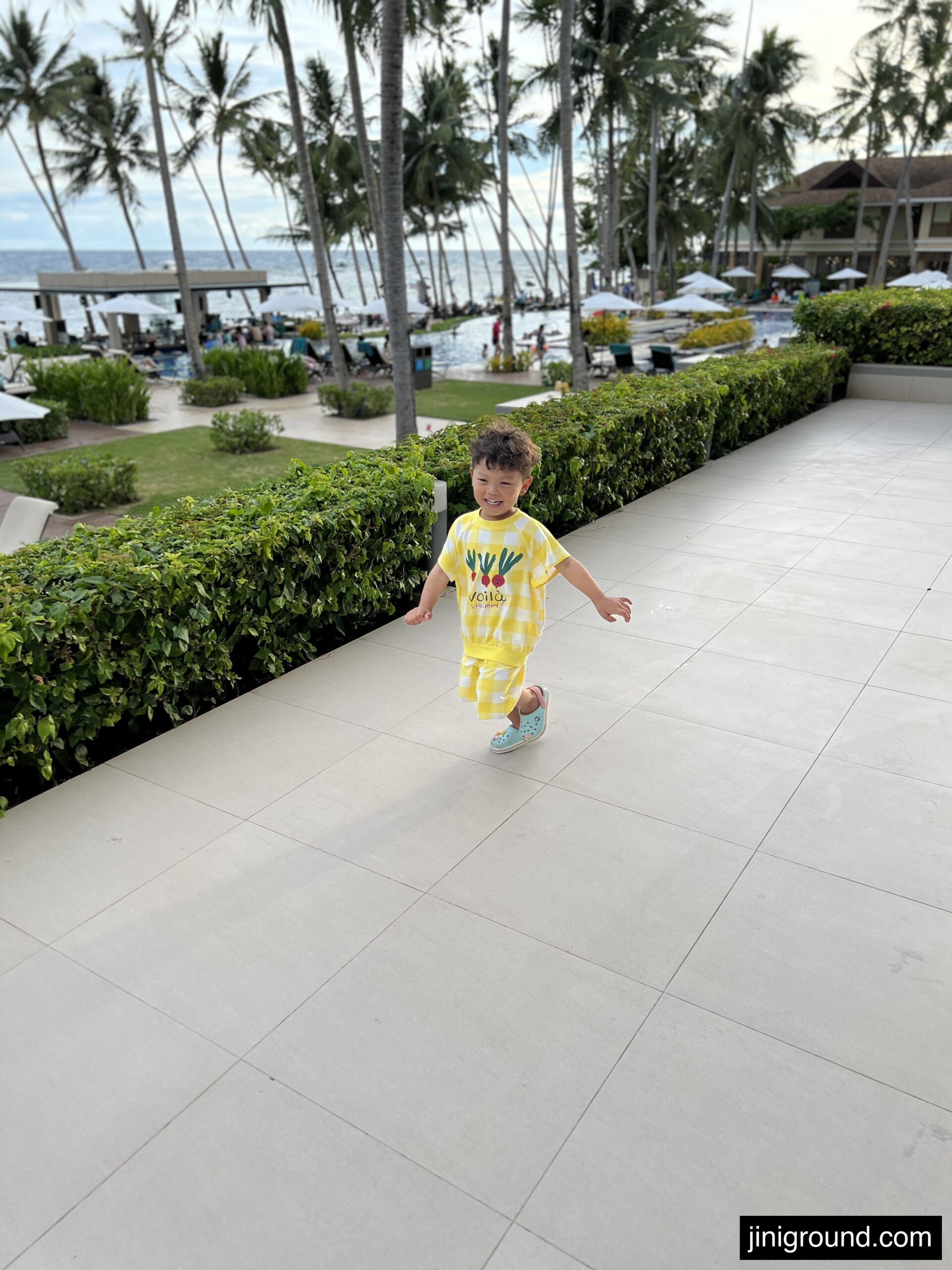 Toddler in yellow shirt walking on beachfront resort grounds Bohol Philippines