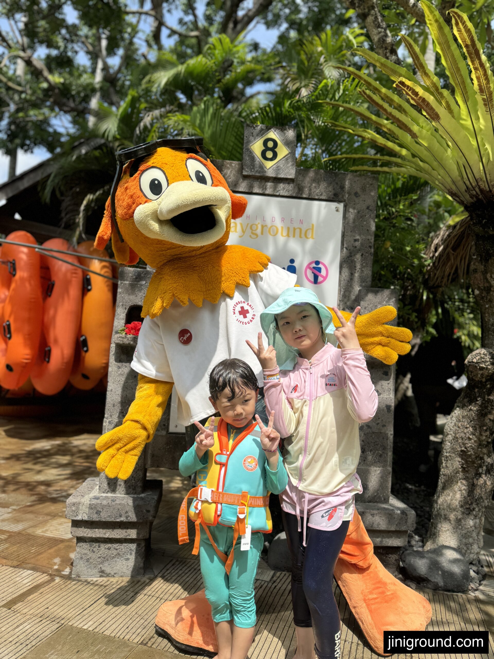 Children posing with colorful Waterbom park character mascot in costume