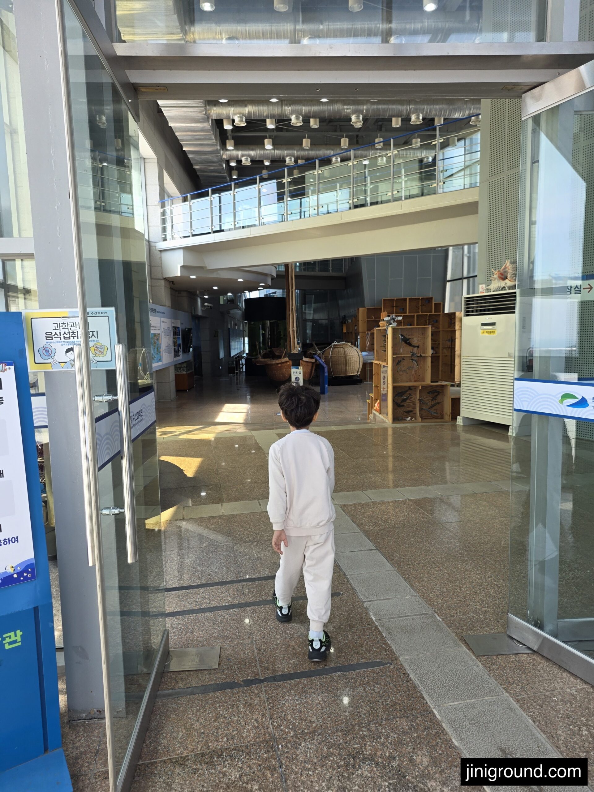 boy entering Tongyeong Marine Science Museum lobby looking at fish exhibits