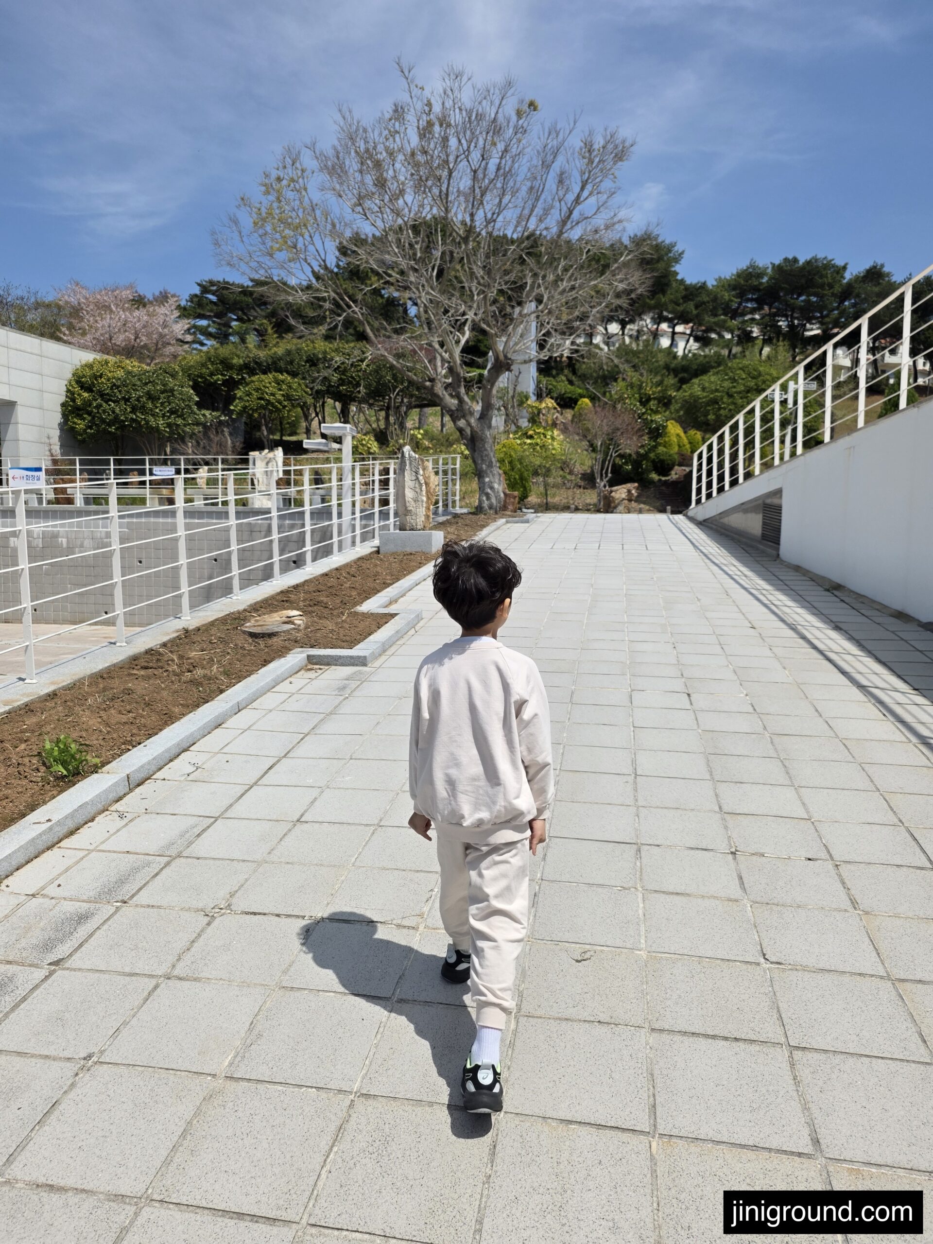 7-year-old boy walking at Tongyeong Marine Science Museum entrance on a sunny April day