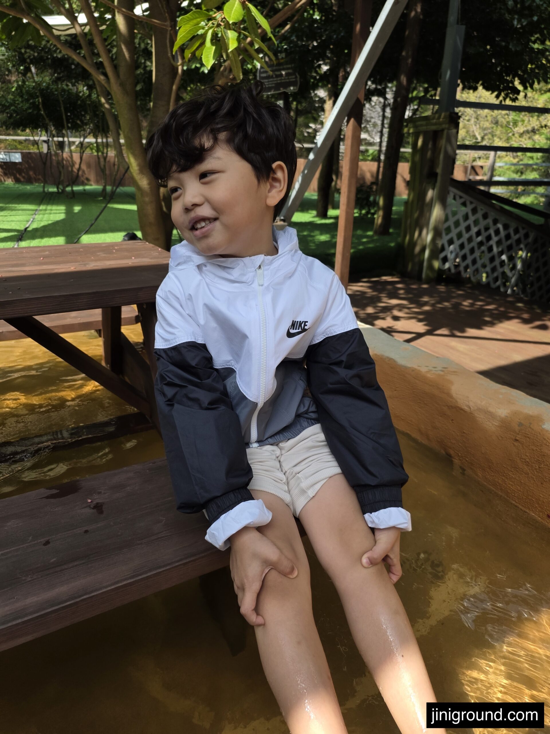 7-year-old boy foot soaking in outdoor water basin on wooden deck at Napoli Farm Tongyeong