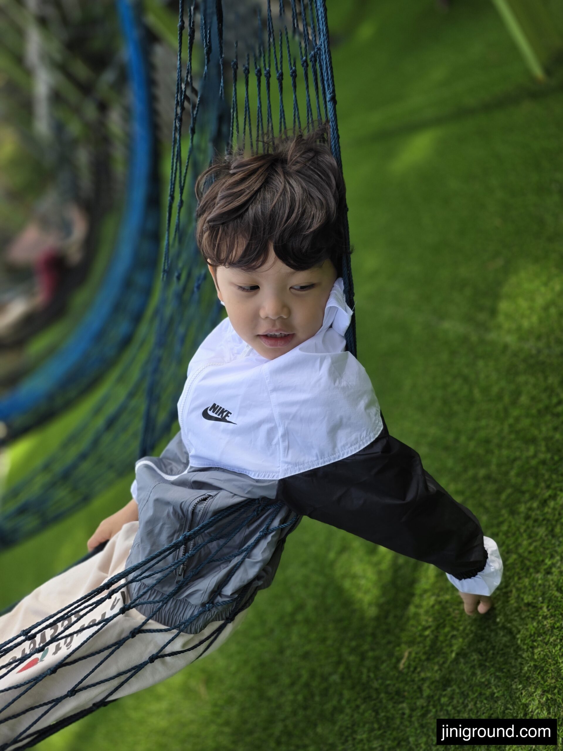 boy lying in rope hammock net on green lawn at Napoli Farm Tongyeong