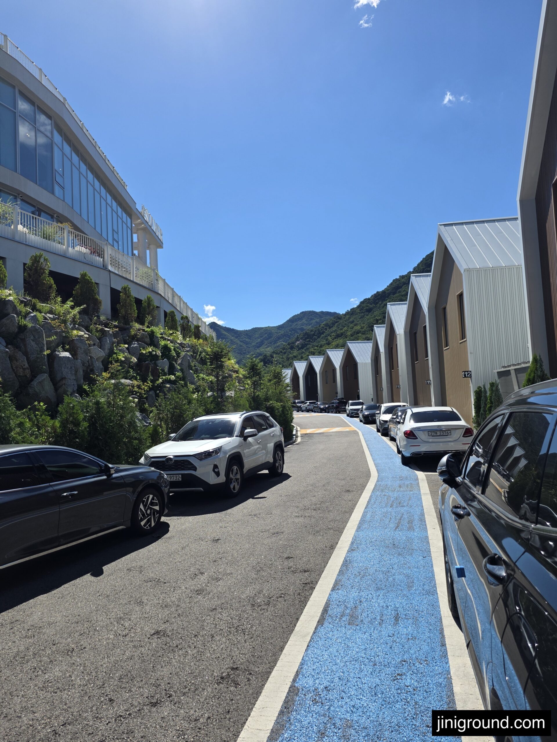 Gapyeong pool villa gabled cabins lined up along a mountain valley driveway in summer
